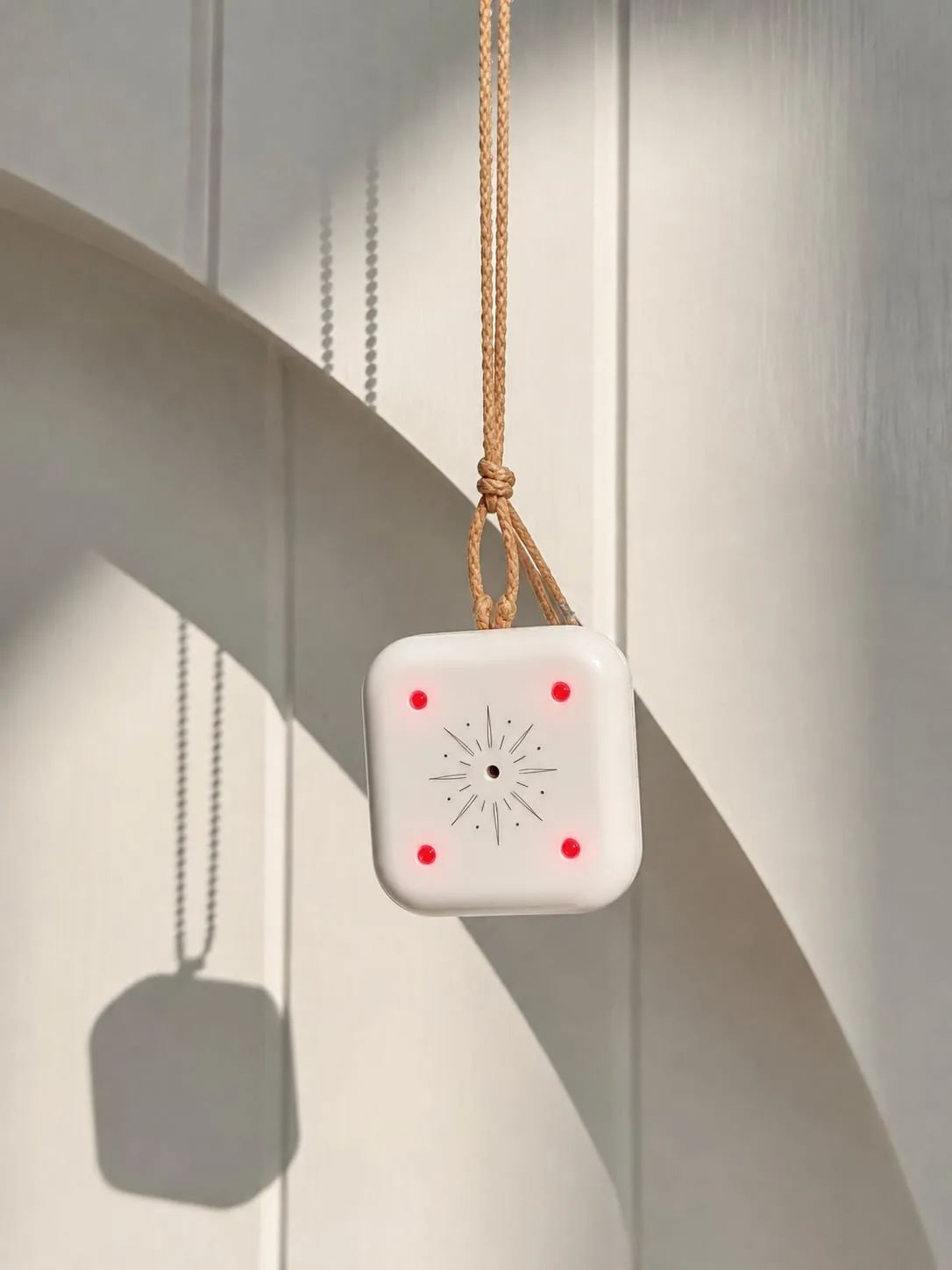 Mandala Breeze wearable wellness device on a gold cord in natural light