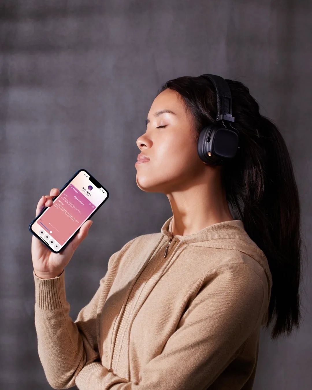 Woman listening with headphones and holding the SoulSync application